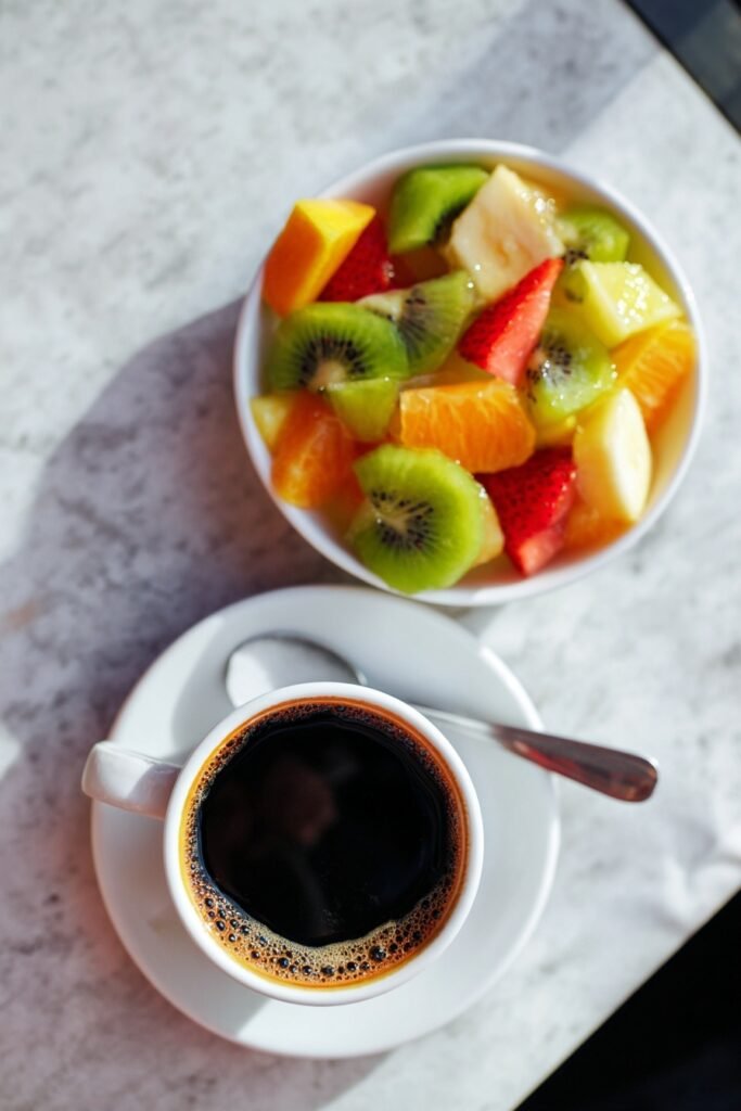 cup of coffee and a fresh fruit salad in a bowl